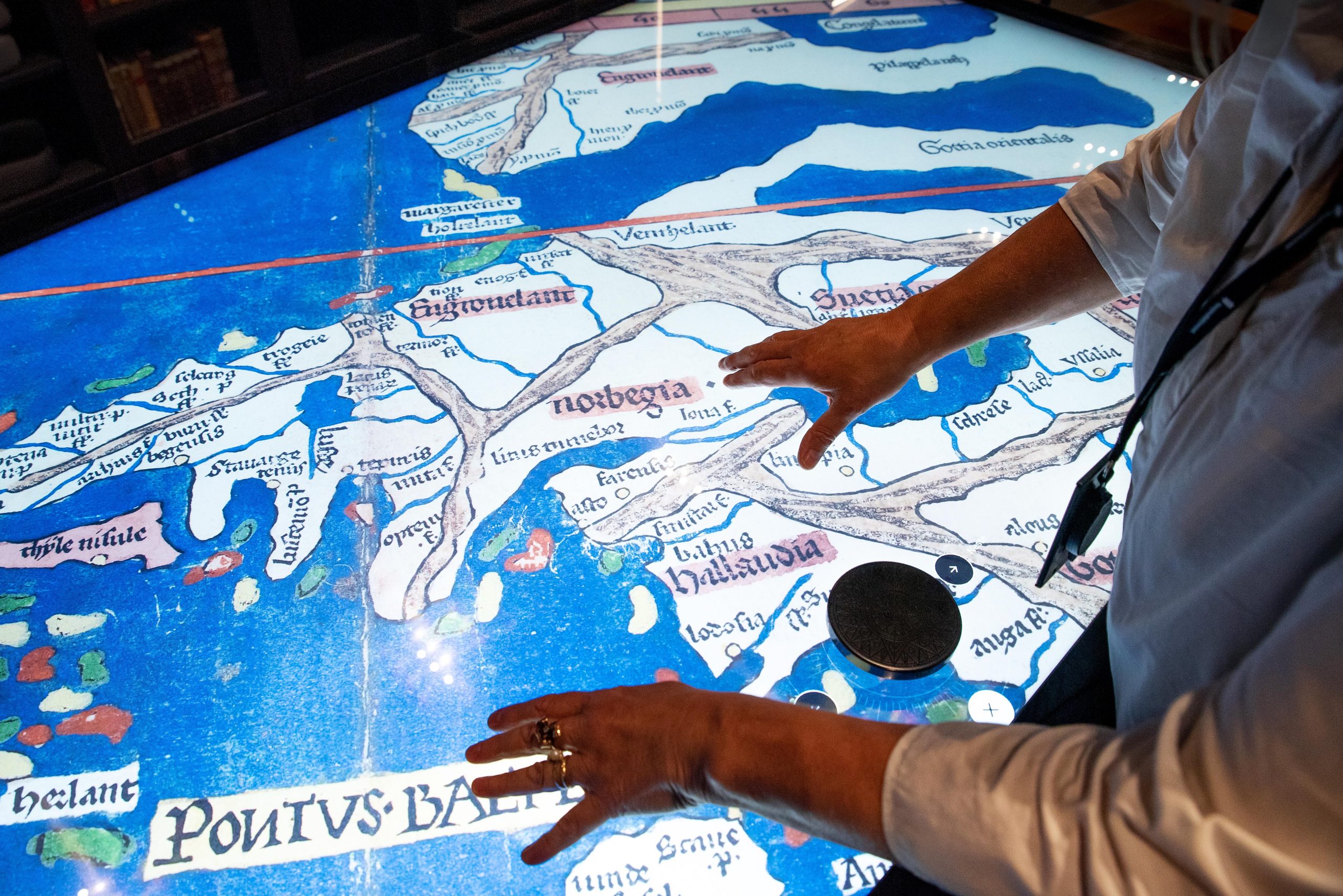 A person rests their hands on the touch screen of an archived map.